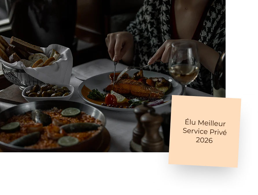 Personne en train de déguster un pavé de saumon grillé servi avec une paella aux fruits de mer et une corbeille de pain.